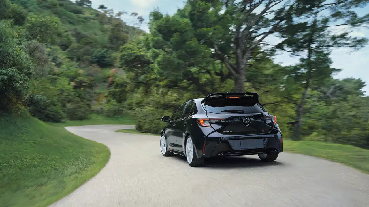 Rear view of a 2027 Toyota Corolla Hatchback on a winding road