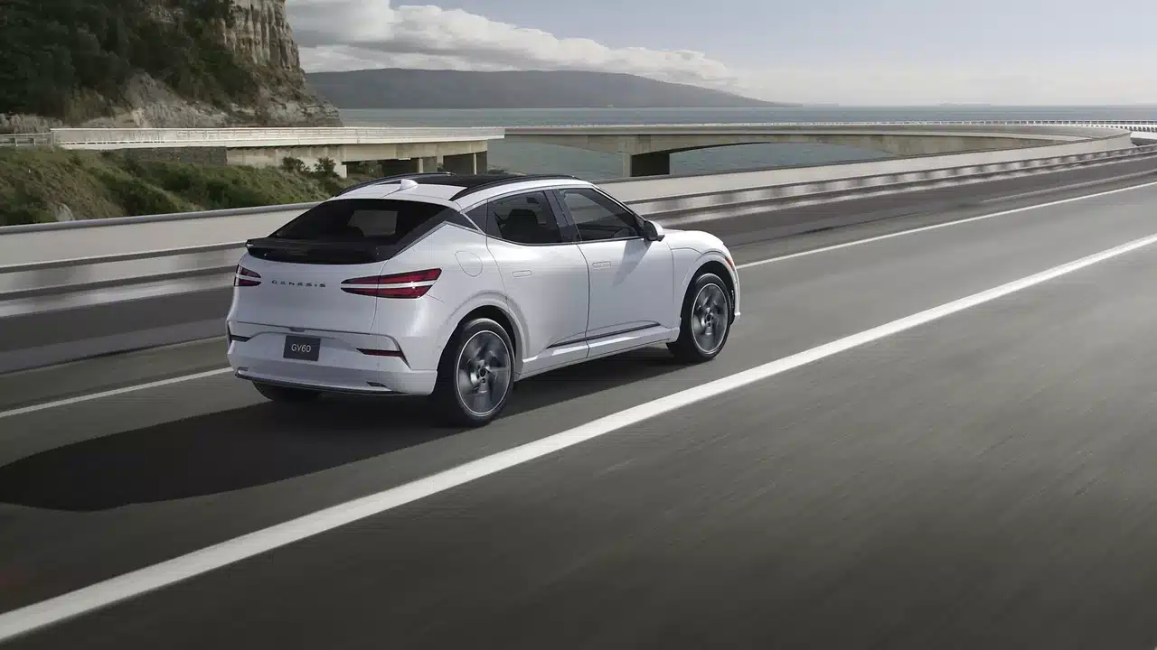 White 2027 Genesis GV60 driving on a coastal road