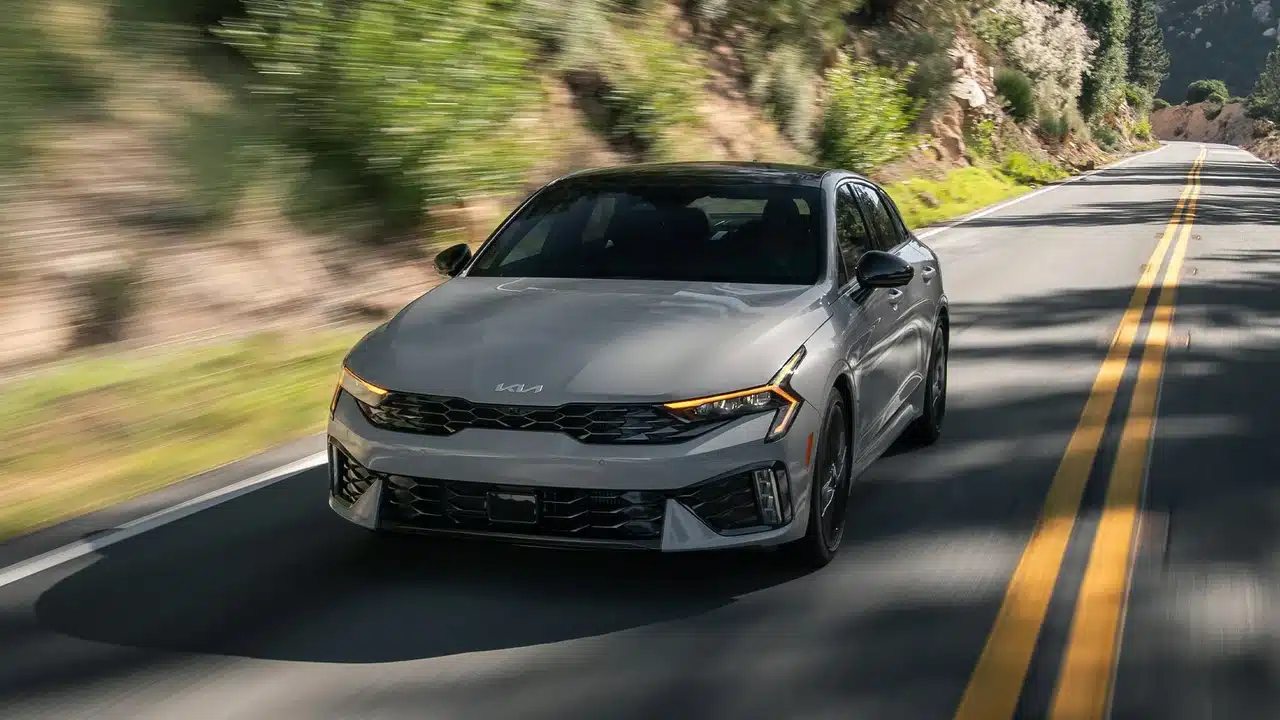 2027 Kia K5 GT driving on a wooded road