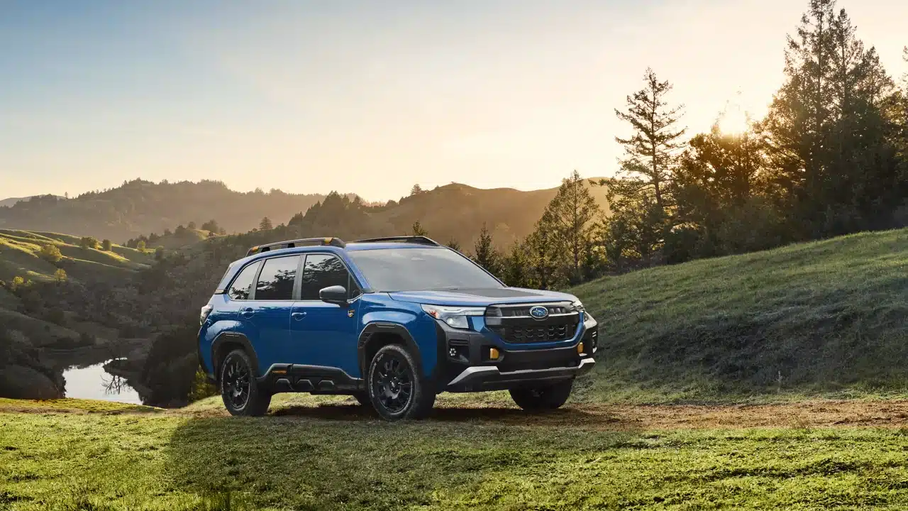 Blue 2027 Subaru Forester Wilderness parked beside wooded hills
