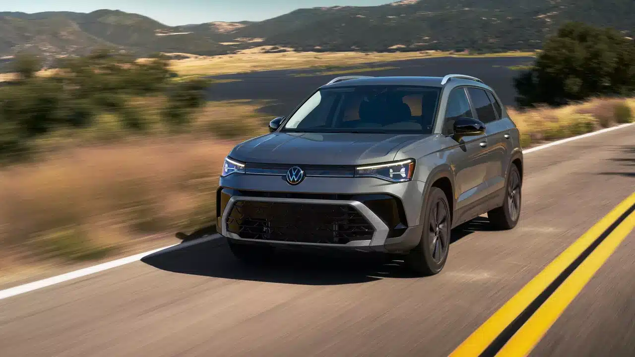 Gray 2027 Volkswagen Taos Sport driving beside a mountain lake