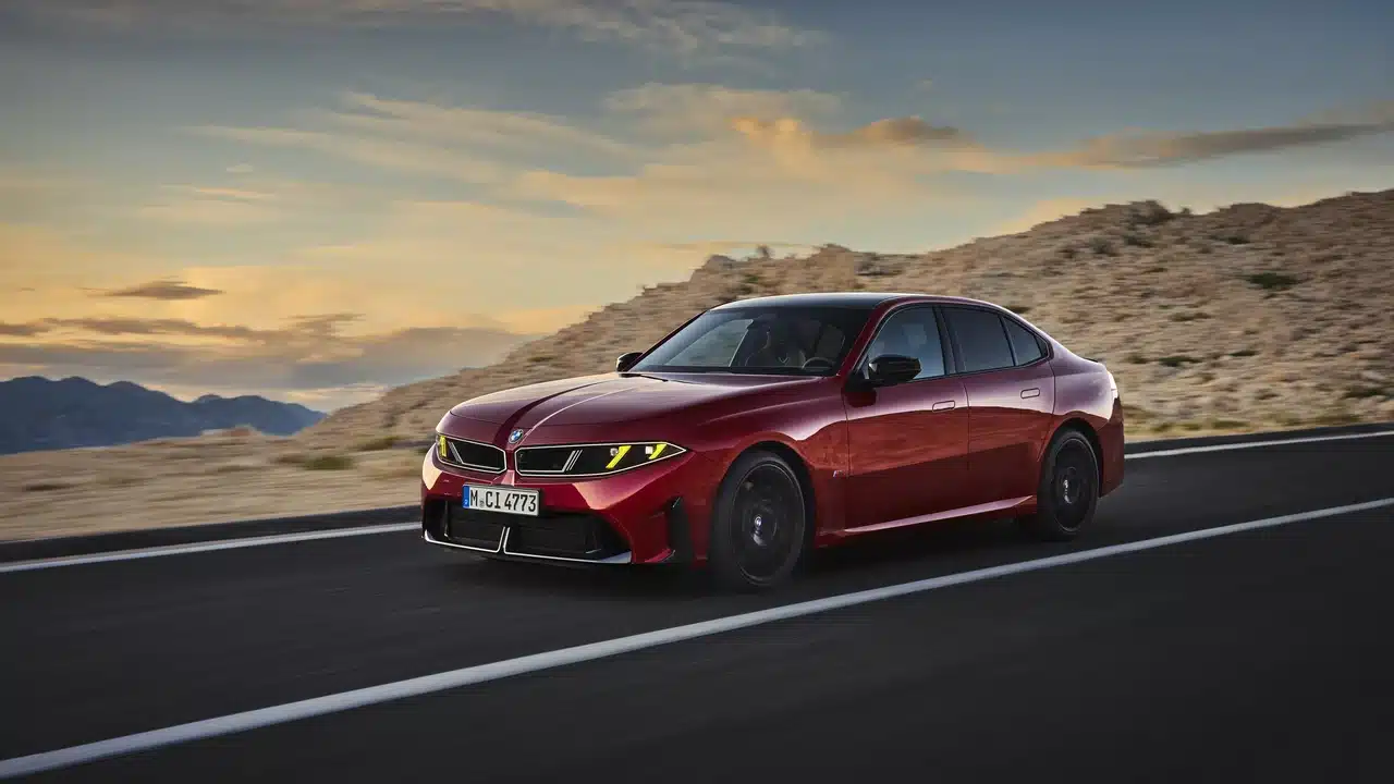 Red 2027 BMW M350 xDrive driving on a mountain road at sunset