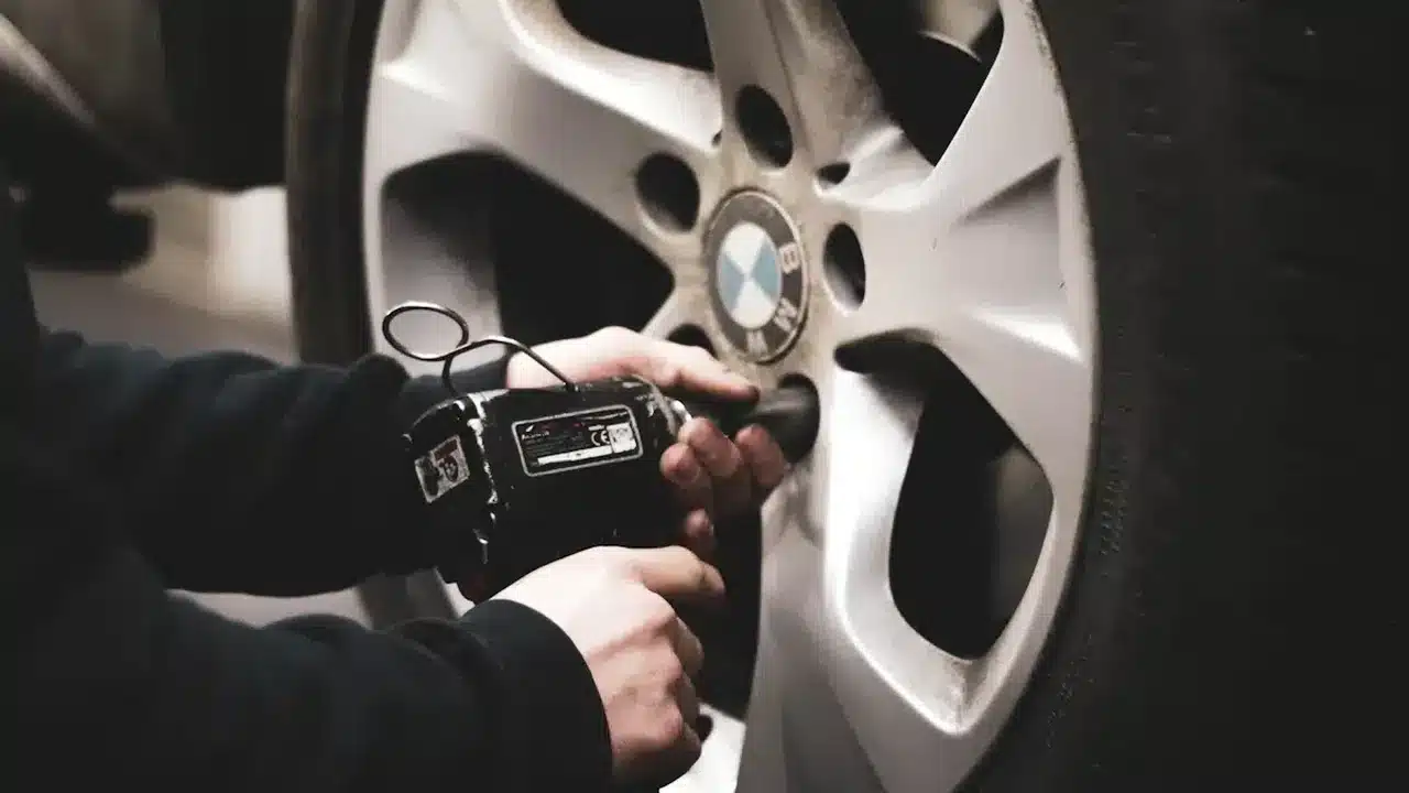 Technician using a tool beside a vehicle wheel