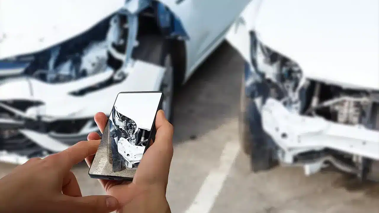 Driver photographing collision damage for an insurance claim