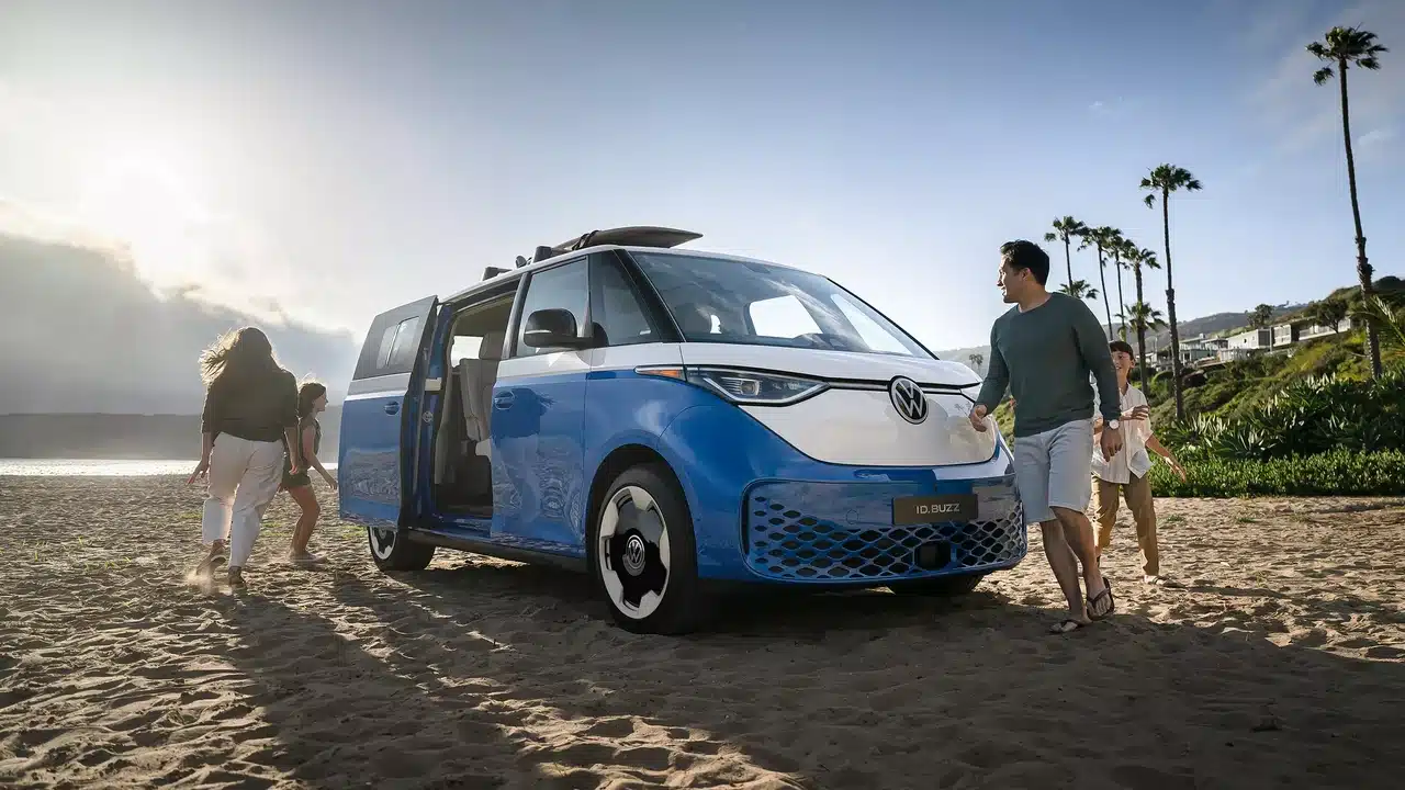 Blue and white 2025 Volkswagen ID. Buzz beside a beach