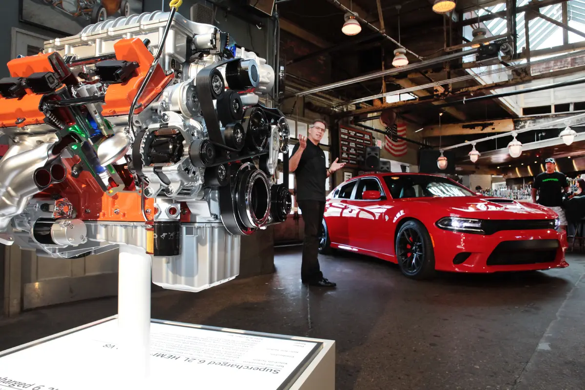 Supercharged Hemi engine displayed beside the 2015 Dodge Charger SRT Hellcat